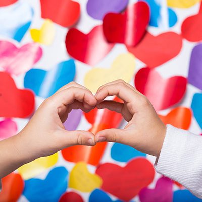 Kids hands make a heart on a colored valentines background Kids hands make a heart on a colored valentines background