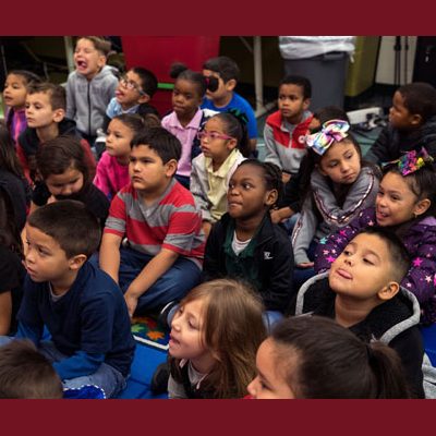 Kindergartners at Gloria Hicks mimic giraffes by trying to touch their tongues to their ears.