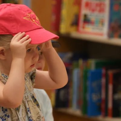 Little girl putting on Giraffe pink cap